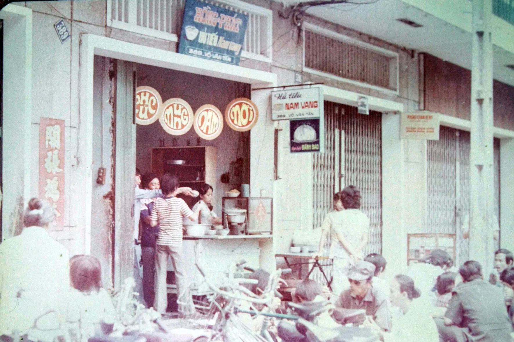 Faded colour photo of the early Hồng Phát shopfront under its hủ tiếu Nam Vang sign, with customers outside